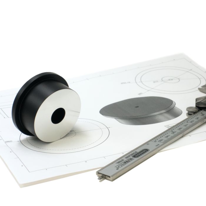 Apertura 2 Inch Collimation Cap laid on top of a printout its technical drawing, with a pair of calipers set down next to it.